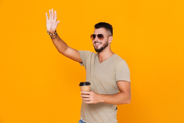 Portrait d'un jeune homme décontracté gai à lunettes de soleil