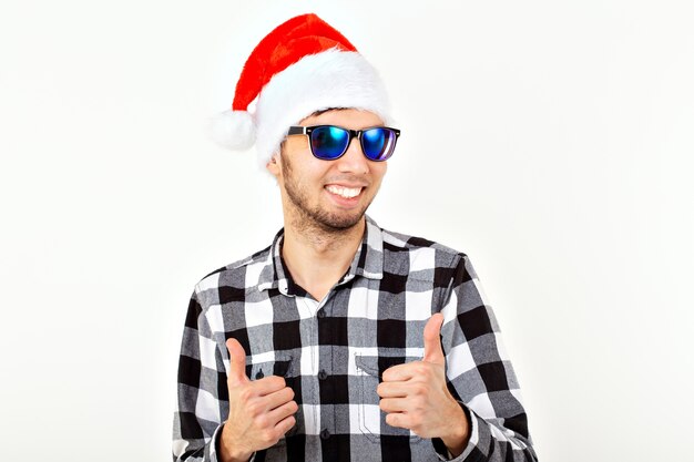 Portrait d'un jeune homme drôle en chapeau de père Noël et barbe sur un espace blanc. Noël.