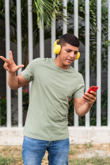 Portrait d'un jeune homme avec des écouteurs marchant dehors dans la ville en écoutant de la musique