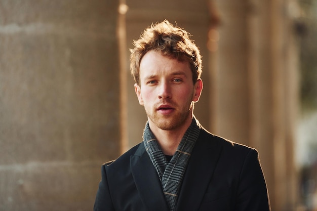 Portrait d'un jeune homme élégant dans des vêtements formels et élégants à l'extérieur de la ville