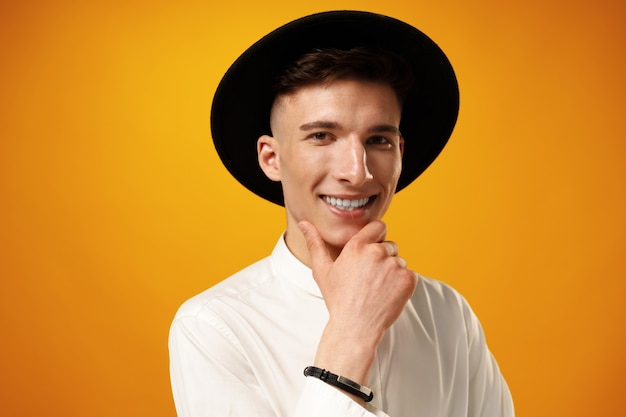 Portrait d'un jeune homme élégant portant un chapeau noir sur fond jaune