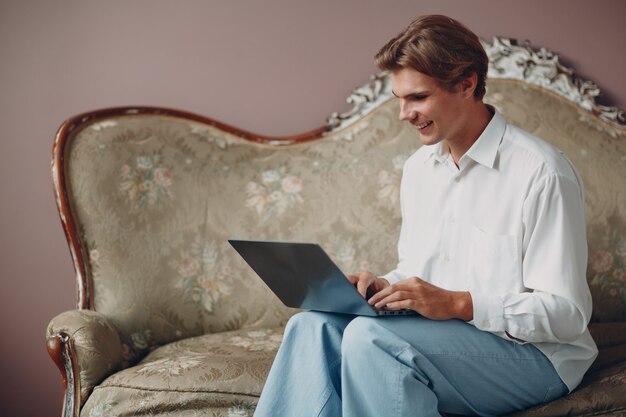 Portrait jeune homme européen assis avec un ordinateur portable au studio