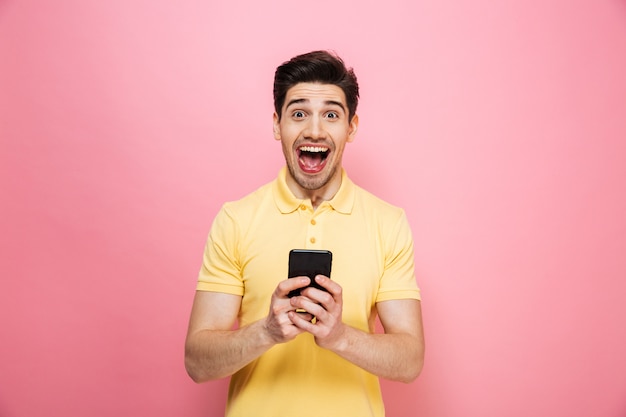 Portrait d'un jeune homme excité tenant un téléphone mobile