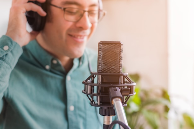 Portrait d'un jeune homme exécutant un podcast en direct de chez lui, il a des écouteurs