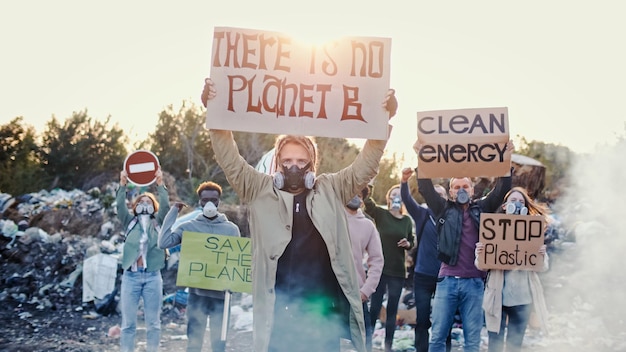 Portrait d'un jeune homme et d'une femme militante avec une affiche appelant à prendre soin de l'environnement en arrière-plan combattant les personnes qui protestaient contre la pollution par les ordures restant à la décharge dans la périphérie de la ville