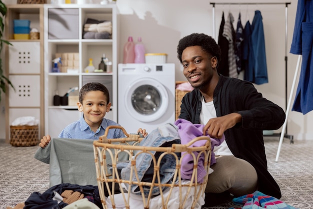 Portrait de jeune homme avec frère plier le linge trier les vêtements dans la machine à laver matin de nettoyage des tâches ménagères