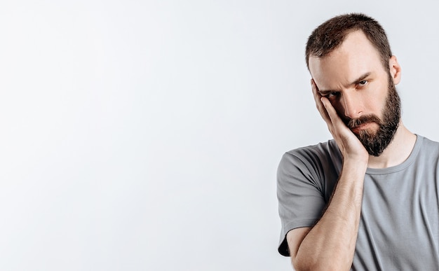 Portrait de jeune homme gai souriant tout en regardant la caméra tenant les mains sur les côtés sur fond blanc avec un espace pour la publicité des maquettes