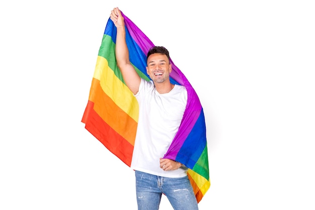 Portrait d'un jeune homme gay souriant tenant un drapeau lgbtqi sur fond blanc