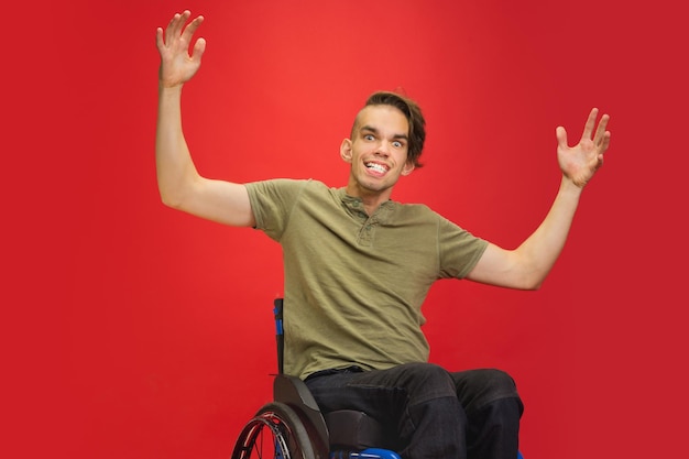 Portrait de jeune homme handicapé caucasien isolé sur fond de studio rouge