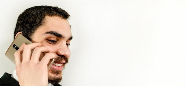 Portrait d'un jeune homme heureux avec une barbe parlant sur un téléphone portable