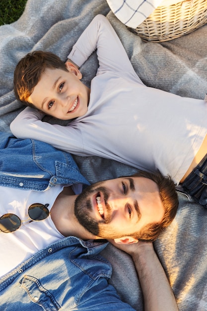 Photo portrait d'un jeune homme heureux s'amusant avec son petit frère ou son fils à l'extérieur dans le parc se trouve