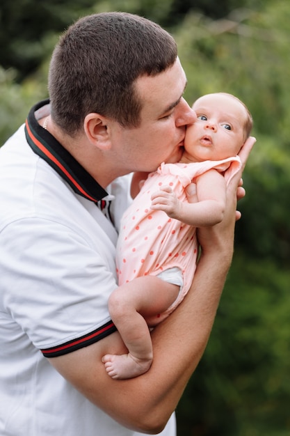 Portrait de jeune homme heureux tenant et embrassant son bébé mignon nouveau-né à l'extérieur