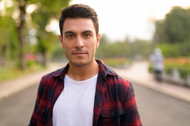 Portrait de jeune homme hipster hispanique beau dans le parc à l'extérieur