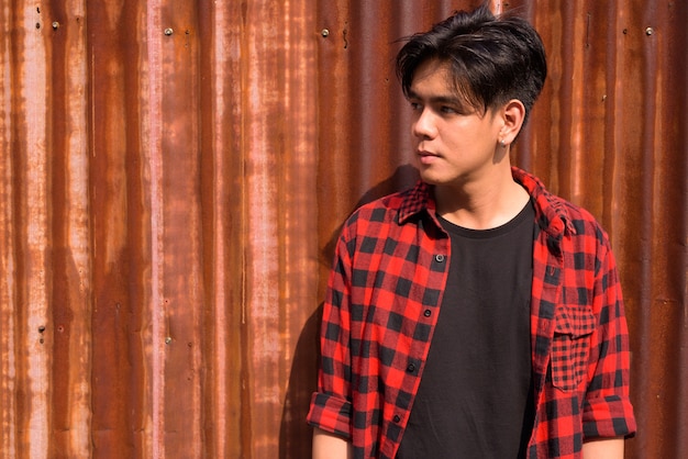 Portrait de jeune homme hipster philippin beau contre le mur de tôle de fer rouillé dans les rues à l'extérieur