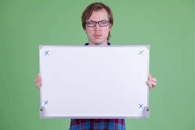 Portrait de jeune homme hipster scandinave beau avec des lunettes contre clé chroma ou mur vert