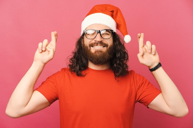 Portrait de jeune homme hispter barbu heureux croisant les doigts et souhaitant