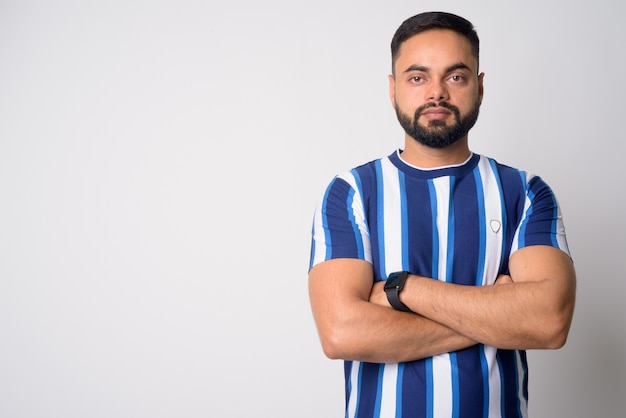 Portrait de jeune homme indien barbu beau contre le mur blanc