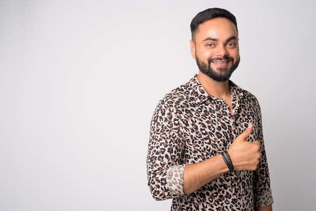 Portrait de jeune homme indien barbu beau contre le mur blanc