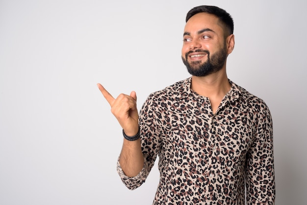 Portrait de jeune homme indien barbu beau contre le mur blanc