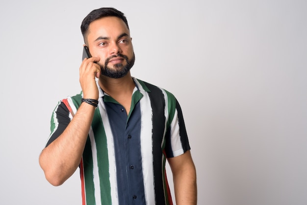 Portrait de jeune homme indien barbu beau contre le mur blanc