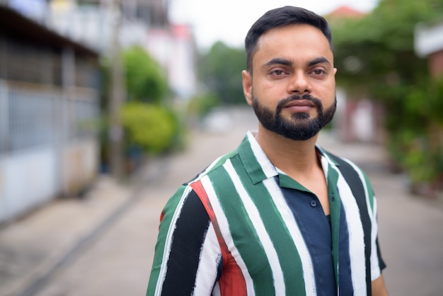 Portrait de jeune homme indien barbu beau dans les rues à l'extérieur