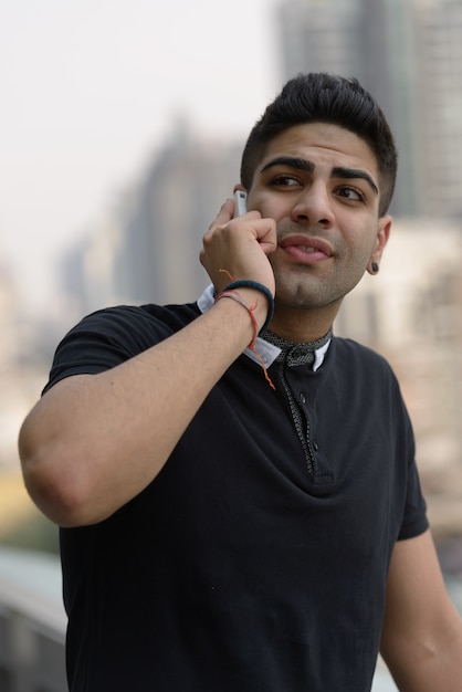 Portrait de jeune homme indien beau contre vue sur la ville