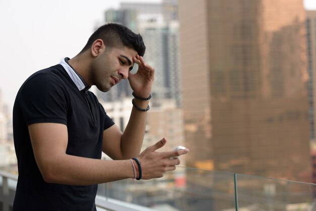 Portrait de jeune homme indien beau contre vue sur la ville