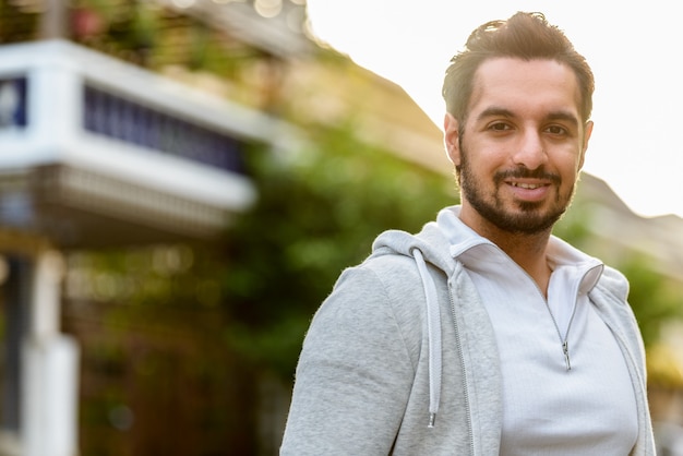 Portrait de jeune homme indien heureux souriant à l'extérieur