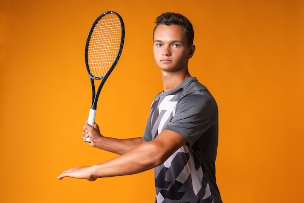 Portrait d'un jeune homme joueur de tennis sur orange