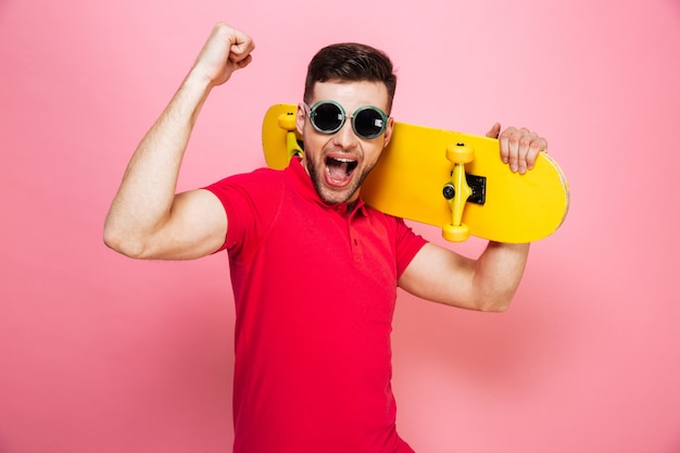 Portrait d'un jeune homme joyeux à lunettes de soleil célébrant