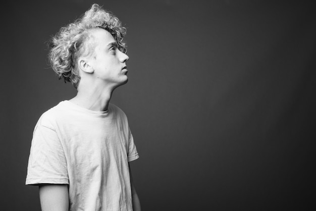 Portrait de jeune homme maigre aux cheveux bouclés sur gris en noir et blanc