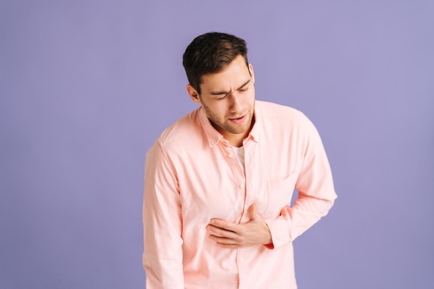 Portrait d'un jeune homme malheureux ressentant une douleur soudaine à l'estomac une détresse abdominale sévère souffrant de nausées allant vomir en studio