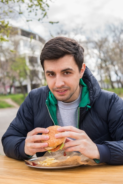 Un portrait de jeune homme mangeant un hamburger