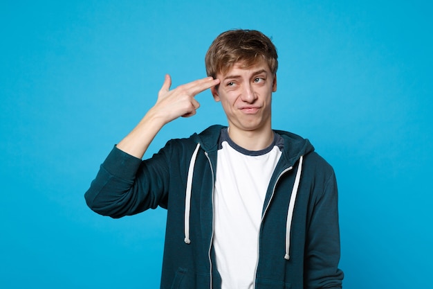 Portrait d'un jeune homme mécontent dans des vêtements décontractés, pointer du doigt la tête comme s'il s'était tiré isolément.