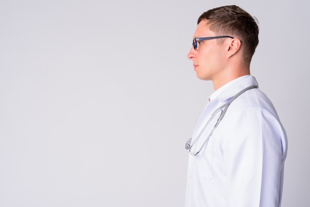 Portrait de jeune homme médecin portant des lunettes contre un mur blanc