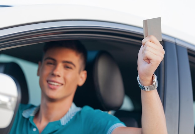 Portrait de jeune homme montrant le permis de conduire dans sa voiture