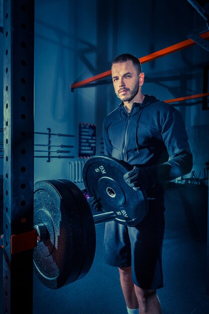 Portrait de jeune homme musclé super fit travaillant dans une salle de sport avec haltères