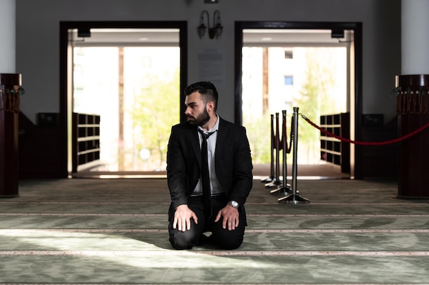 Le portrait d'un jeune homme musulman adulte prie dans la mosquée