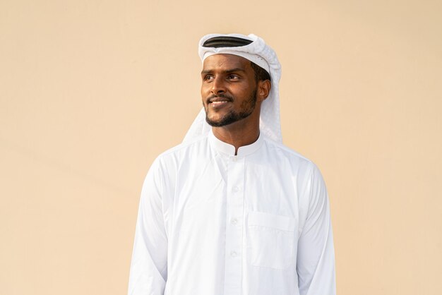 Portrait de jeune homme musulman africain portant des vêtements religieux une écharpe contre un mur uni