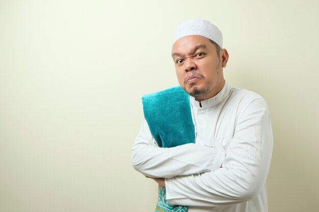 Portrait D'un Jeune Homme Musulman Asiatique Pointant Sur Sa Montre-bracelet, Patron Du Directeur Donnant Un Avertissement Sur Le Concept De Temps. Le Gars A L'air Fou Contre Le Mur D'ivoire