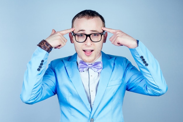 Portrait d'un jeune homme nerd gay avec des lunettes, dans un élégant costume-cravate pense