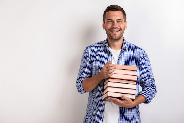 Portrait de jeune homme nerd heureux tenant des livres dans ses mains. Retour à l&#39;école