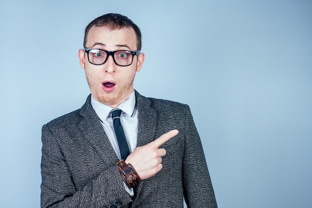 Portrait d'un jeune homme nerd à lunettes et dans un costume élégant pointe avec ses doigts