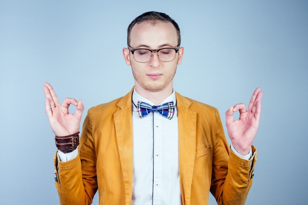 Portrait d'un jeune homme nerd à lunettes, dans un élégant costume et cravate médite