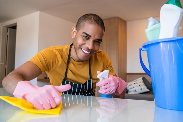 Portrait d'un jeune homme nettoyant la table à la maison