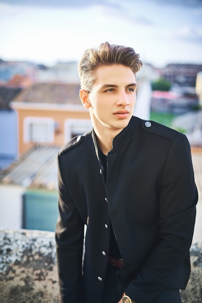 Portrait de jeune homme en noir posant dans la rue