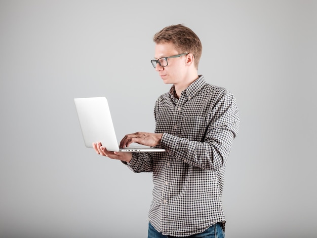Portrait de jeune homme avec ordinateur portable isolé sur fond gris