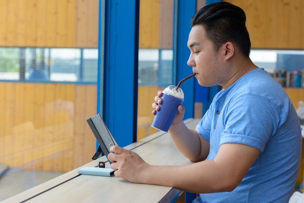 Portrait de jeune homme philippin en surpoids beau se détendre au café