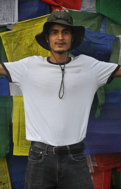 Portrait d'un jeune homme portant un chapeau debout contre un drapeau de prière