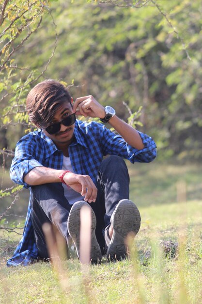 Photo portrait d'un jeune homme portant des lunettes de soleil alors qu'il est assis sur le terrain